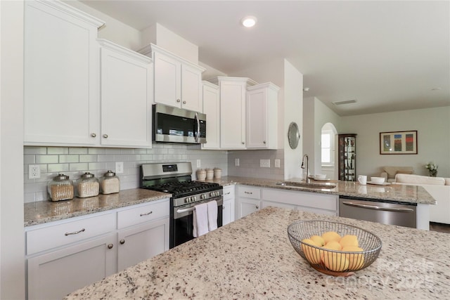 kitchen featuring white cabinets, backsplash, sink, and stainless steel appliances