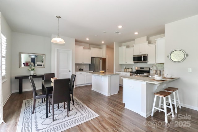 kitchen featuring sink, kitchen peninsula, white cabinets, and stainless steel appliances