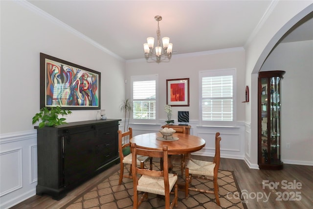 dining area featuring dark wood-type flooring, ornamental molding, and a notable chandelier