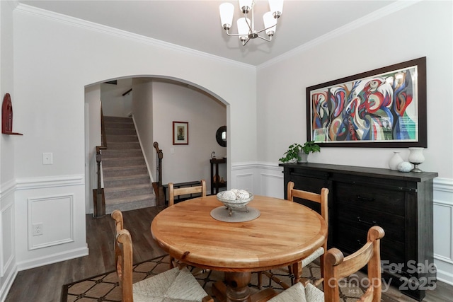 dining area featuring dark wood-type flooring, an inviting chandelier, and ornamental molding