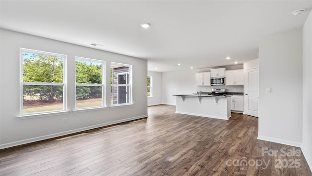 unfurnished living room featuring dark wood-type flooring, recessed lighting, visible vents, and baseboards