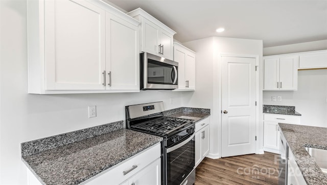 kitchen with recessed lighting, white cabinetry, appliances with stainless steel finishes, dark wood-style floors, and dark stone countertops