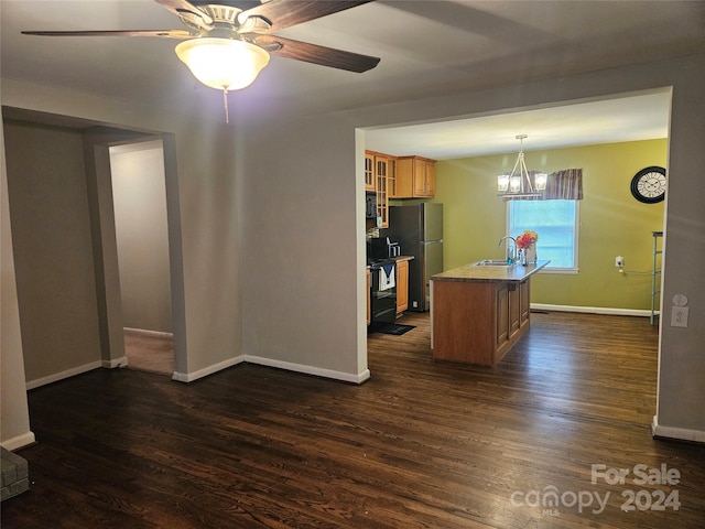 kitchen with pendant lighting, a kitchen island with sink, stainless steel refrigerator, dark hardwood / wood-style floors, and ceiling fan with notable chandelier