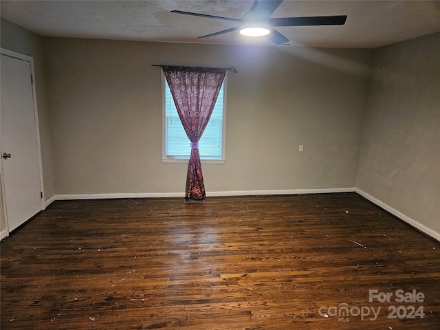 empty room with ceiling fan and dark hardwood / wood-style flooring