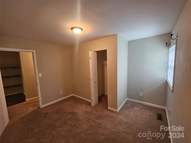 unfurnished bedroom with carpet, a walk in closet, and a closet