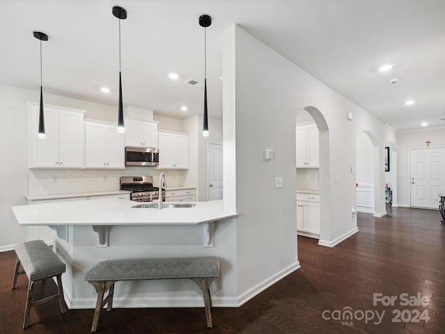 kitchen featuring pendant lighting, stainless steel appliances, dark wood-type flooring, and white cabinetry