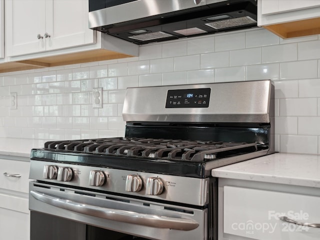 kitchen featuring decorative backsplash, light stone counters, stainless steel appliances, and white cabinets