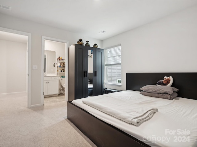 bedroom featuring ensuite bath and light carpet