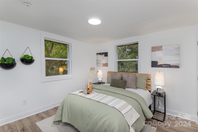 bedroom with multiple windows and hardwood / wood-style flooring