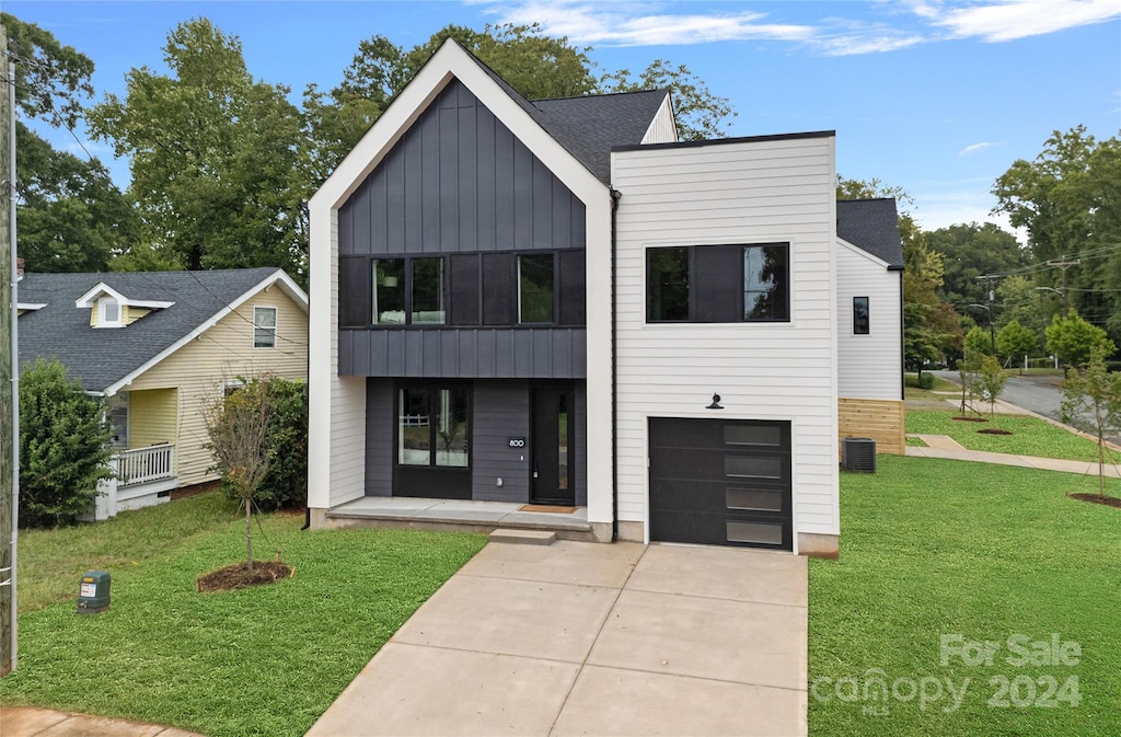 view of front facade with a garage, a porch, cooling unit, and a front lawn