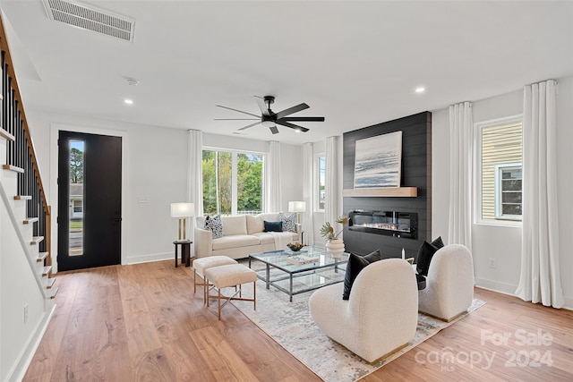 living room with ceiling fan, a large fireplace, and light hardwood / wood-style floors