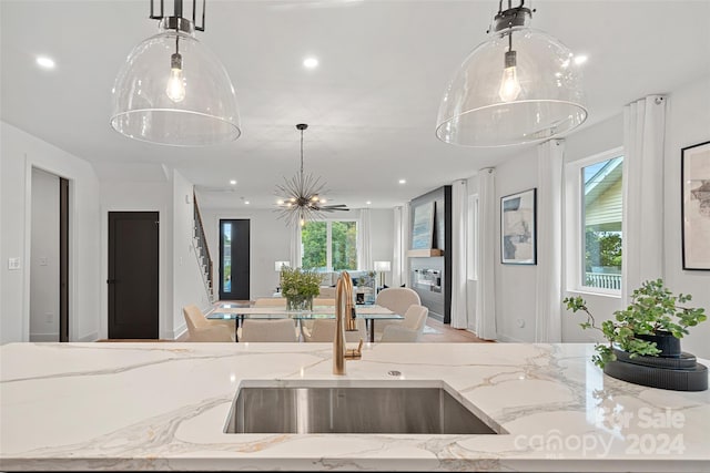 kitchen featuring decorative light fixtures, light stone countertops, and sink