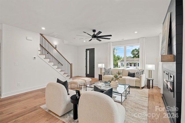 living room with light wood-type flooring, a fireplace, and ceiling fan