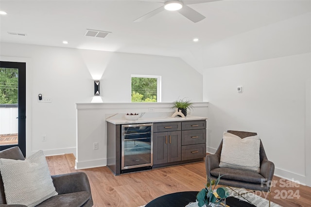 interior space with light wood-type flooring, dark brown cabinets, beverage cooler, lofted ceiling, and ceiling fan