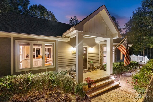 back house at dusk featuring a porch