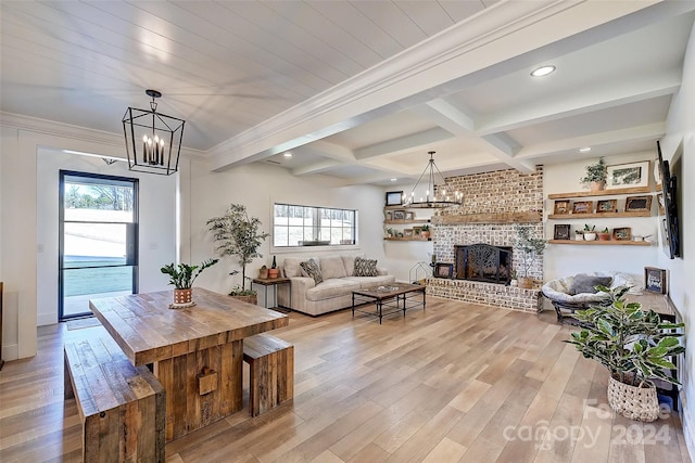 dining space featuring a brick fireplace, an inviting chandelier, light hardwood / wood-style flooring, and a healthy amount of sunlight