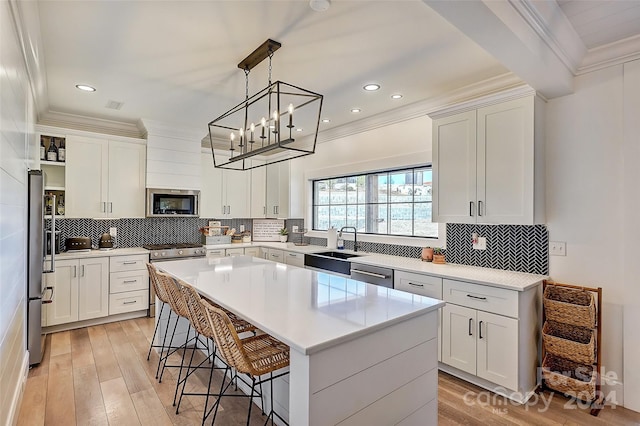 kitchen with white cabinets, stainless steel appliances, light wood-type flooring, and a center island