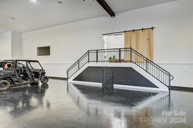 interior space with beam ceiling and a barn door