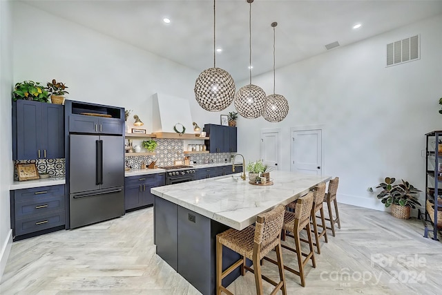 kitchen with premium appliances, wall chimney exhaust hood, a kitchen breakfast bar, decorative light fixtures, and light parquet floors