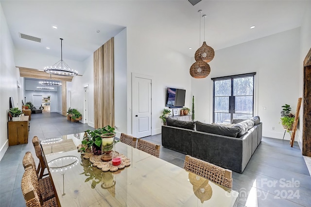 dining space featuring an inviting chandelier, dark tile patterned floors, and a high ceiling