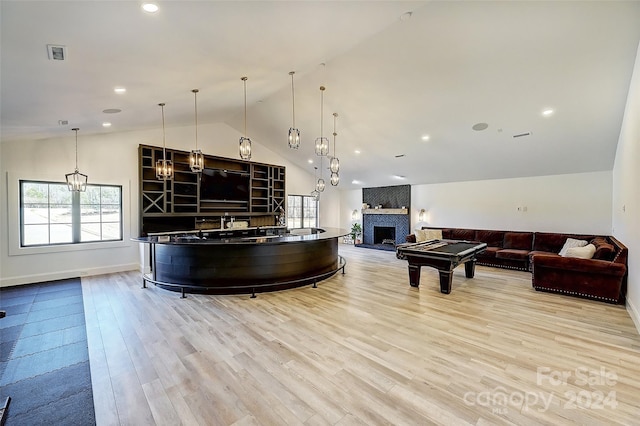 interior space featuring pool table, vaulted ceiling, a fireplace, light hardwood / wood-style flooring, and decorative light fixtures