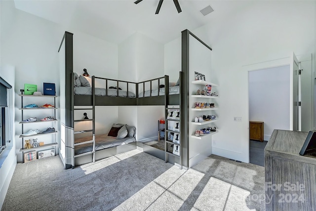 carpeted bedroom with ceiling fan and a towering ceiling