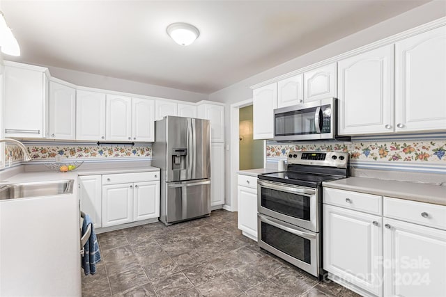 kitchen featuring decorative backsplash, white cabinets, appliances with stainless steel finishes, and sink