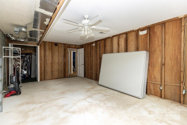 basement with ceiling fan and wood walls