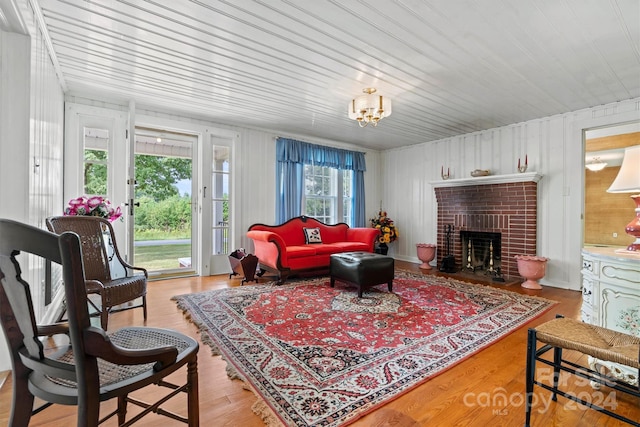 living room featuring a brick fireplace, light hardwood / wood-style floors, a chandelier, and wood ceiling