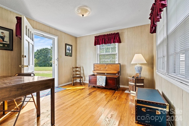 office with wood walls, hardwood / wood-style floors, a healthy amount of sunlight, and a textured ceiling