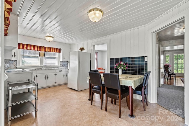 dining space featuring wooden walls, sink, and light carpet