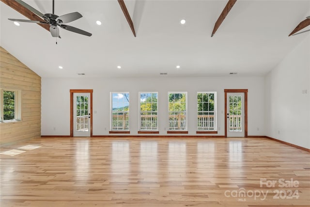 unfurnished living room featuring light hardwood / wood-style flooring, wooden walls, and plenty of natural light