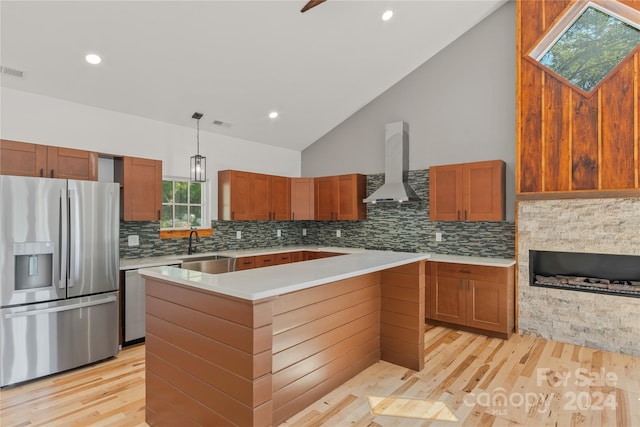 kitchen featuring light hardwood / wood-style floors, wall chimney exhaust hood, a center island, and stainless steel appliances