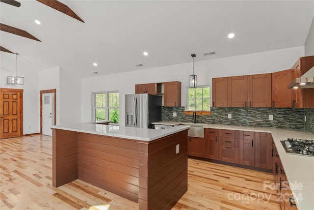 kitchen featuring decorative light fixtures, stainless steel fridge, lofted ceiling, and a center island