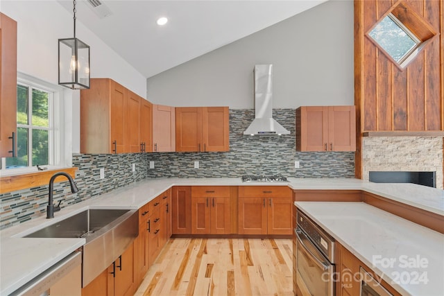 kitchen featuring pendant lighting, lofted ceiling, wall chimney range hood, and tasteful backsplash