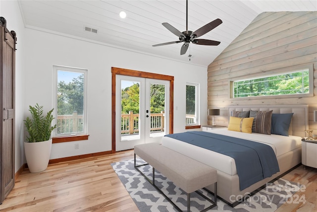 bedroom featuring light wood-type flooring, access to outside, a barn door, high vaulted ceiling, and ceiling fan