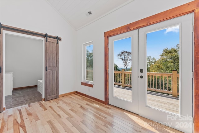 doorway to outside featuring light wood-type flooring, lofted ceiling, french doors, and a barn door