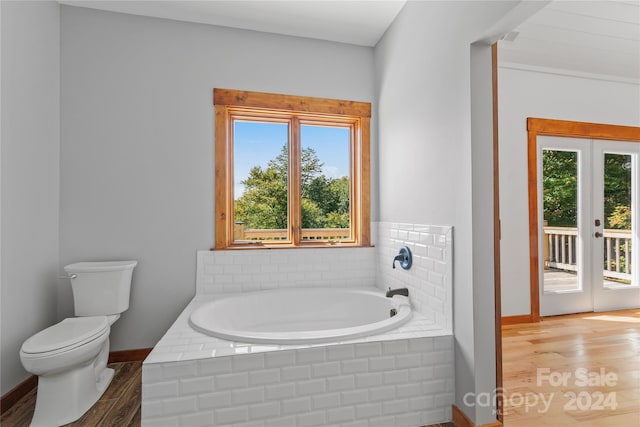 bathroom featuring wood-type flooring, toilet, a healthy amount of sunlight, and a bathing tub