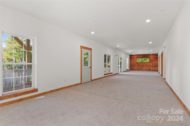 unfurnished living room featuring light colored carpet and a wealth of natural light