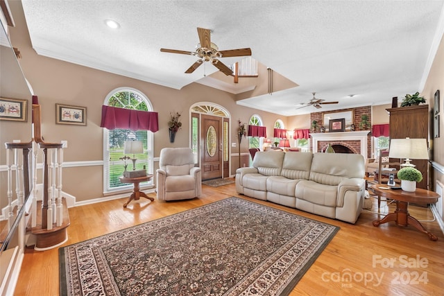 living room with ceiling fan, a textured ceiling, and wood-type flooring