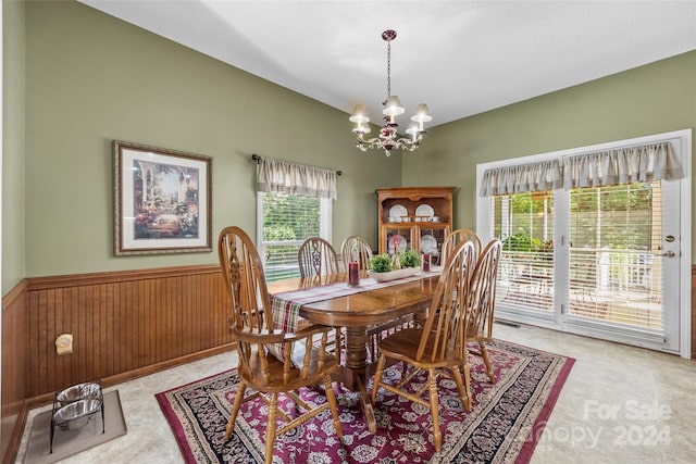 dining space with an inviting chandelier and wood walls