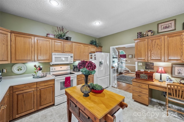 kitchen featuring a textured ceiling, light wood-type flooring, and white appliances