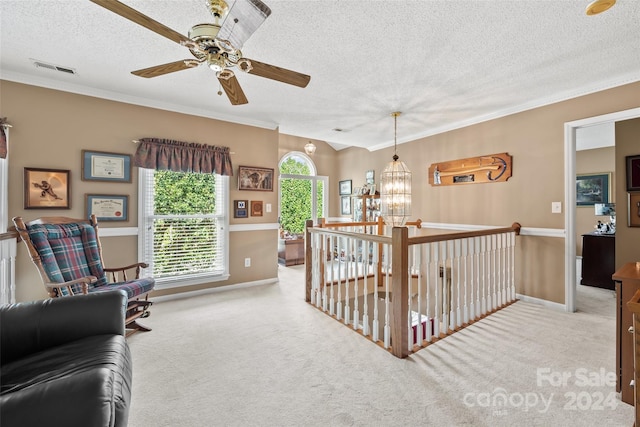 living area with a textured ceiling, ceiling fan with notable chandelier, crown molding, and light colored carpet