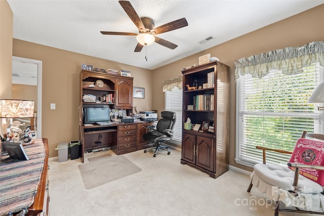 home office with ceiling fan, a textured ceiling, and light carpet