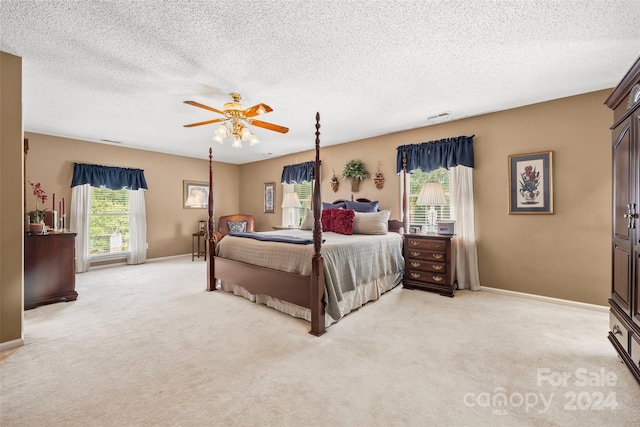 bedroom with ceiling fan, a textured ceiling, and light carpet