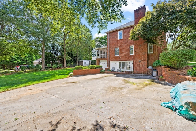 back of house with a garage, a yard, and a sunroom