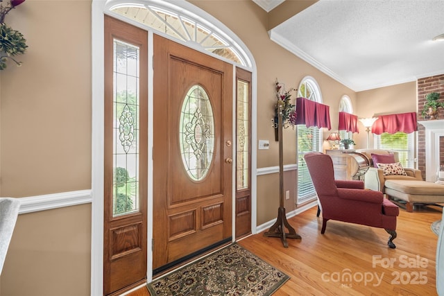 foyer featuring ornamental molding, wood-type flooring, a textured ceiling, and a wealth of natural light