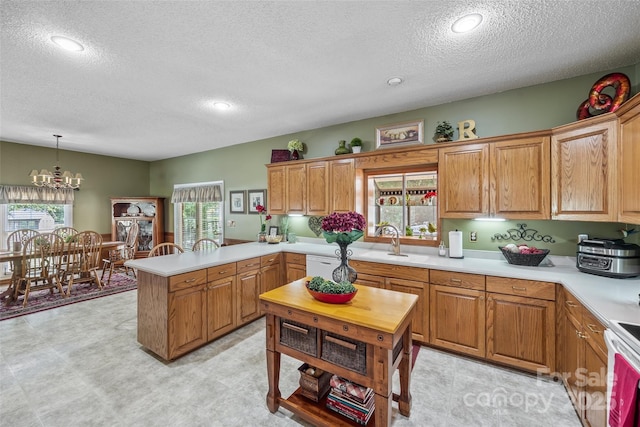 kitchen featuring pendant lighting, sink, a textured ceiling, white electric stove, and a chandelier