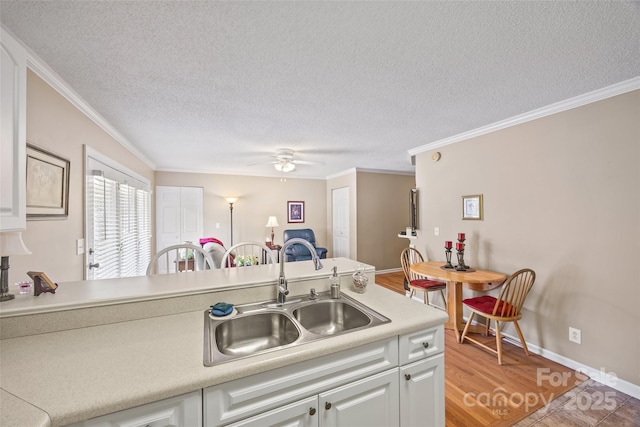 kitchen with white cabinetry, sink, ornamental molding, ceiling fan, and a textured ceiling