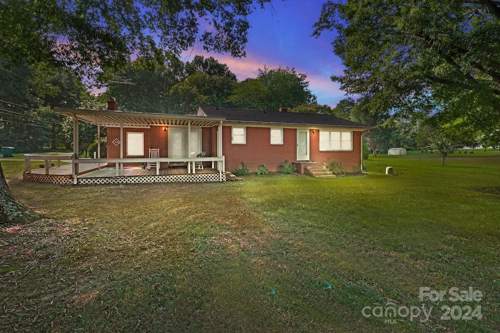 view of front of home featuring a pergola, a deck, and a lawn